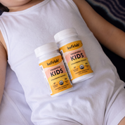 Two kefirlab Kids probiotic shot bottles with white caps, strawberry banana