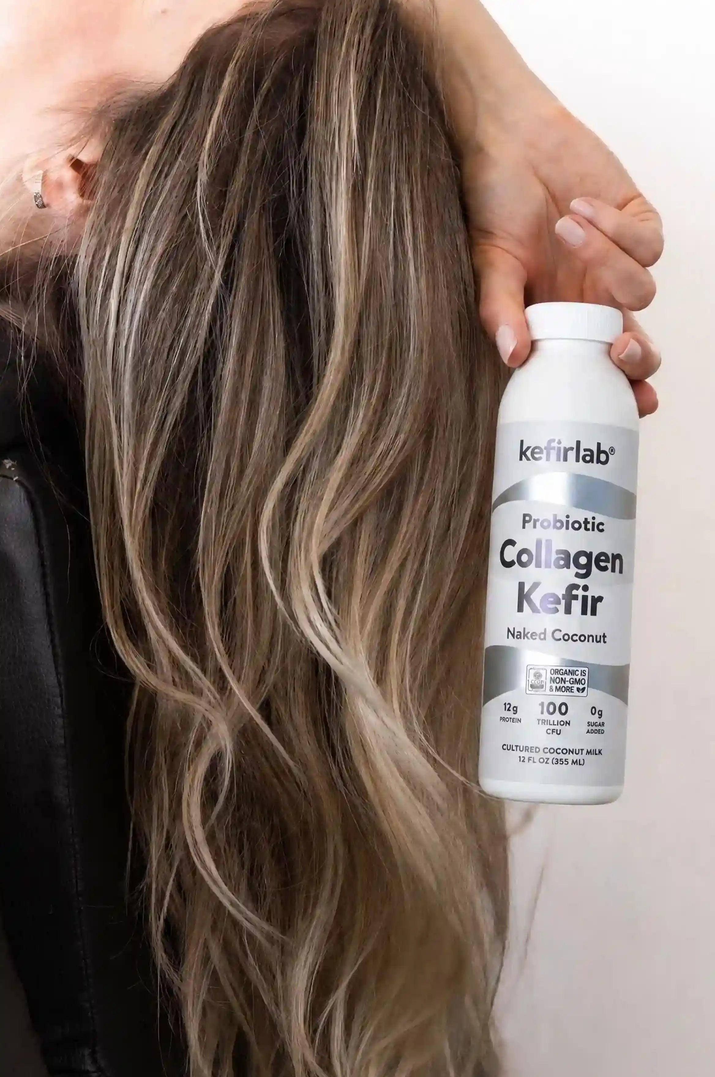Probiotic collagen kefir bottle by kefirlab, held near long hair, Naked Coconut