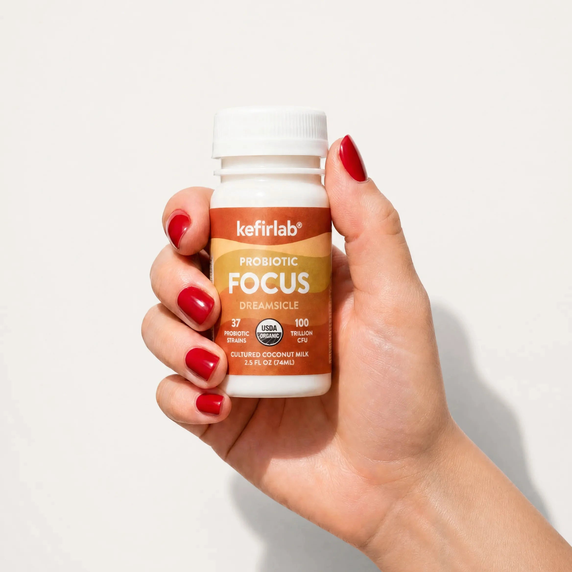 Probiotic shot bottle with white cap, kefirlab label, amber orange