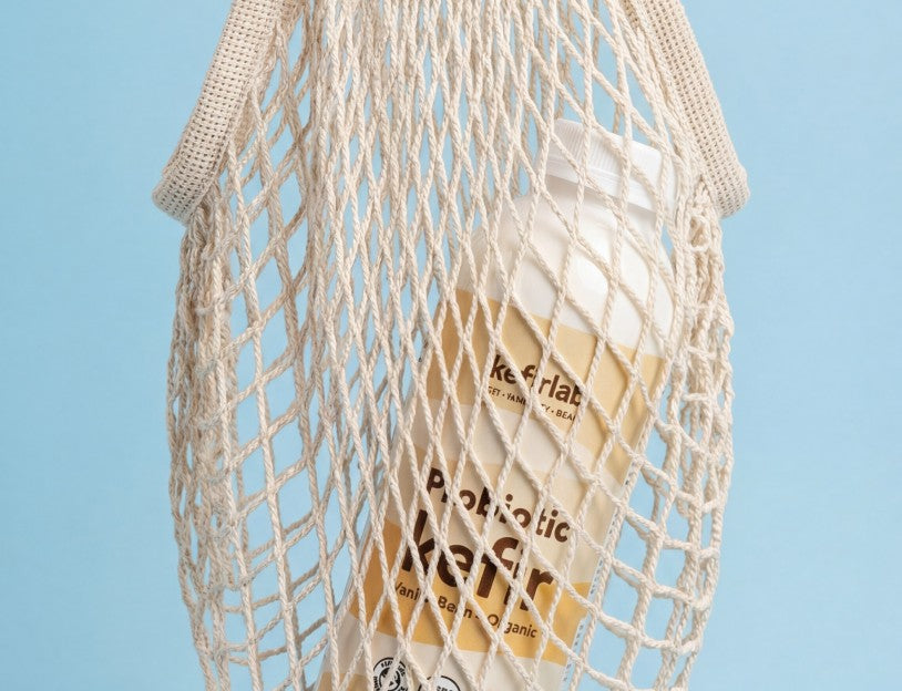 String bag with a Kefir Lab probiotic bottle against a light blue background